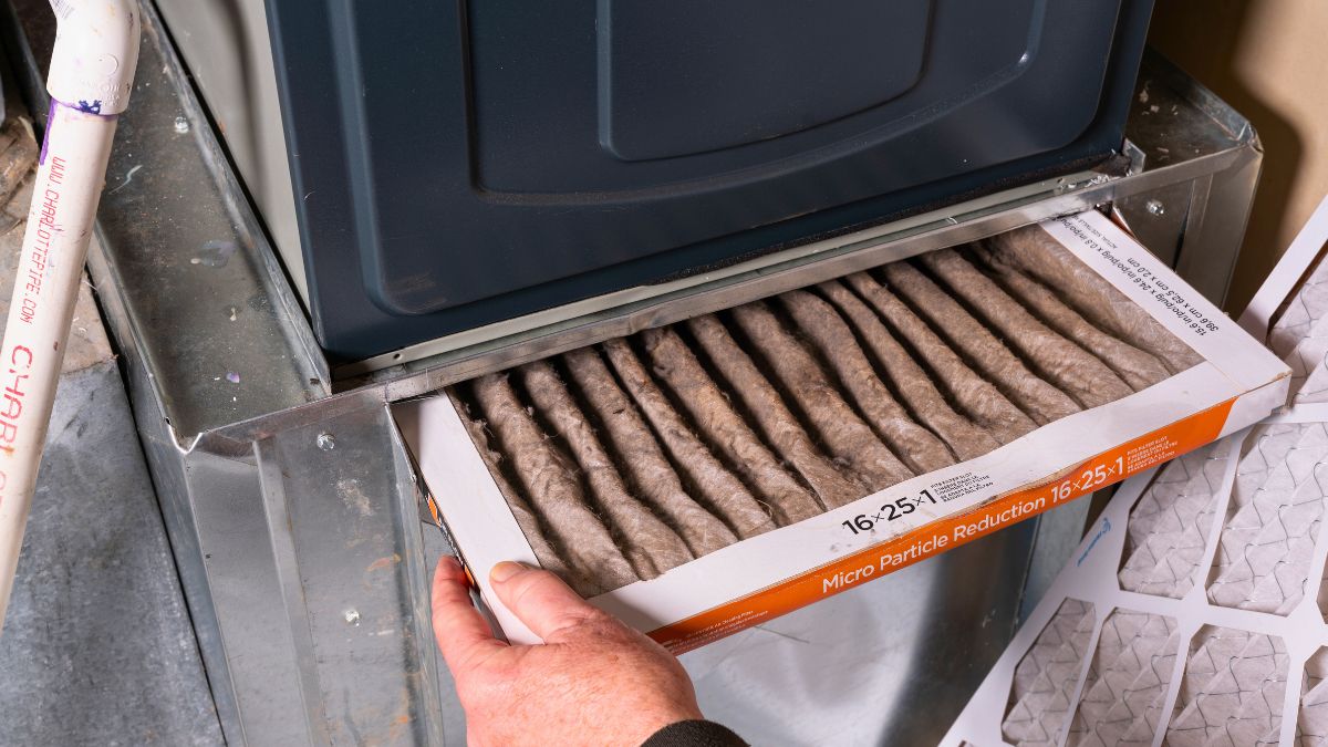 Homeowner checking furnace filter before calling HVAC technician